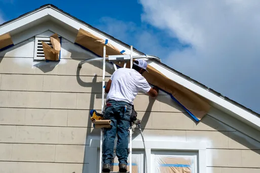 Painter masking a gable vent on an Eastover home before painting